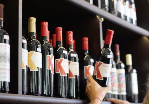 A selection of red wine bottles with bold labels on a store shelf.